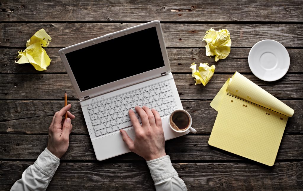 writer discarding drafts next to his laptop