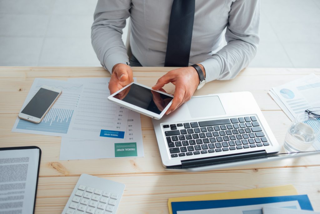 man doing online tasks on his tablet and laptop